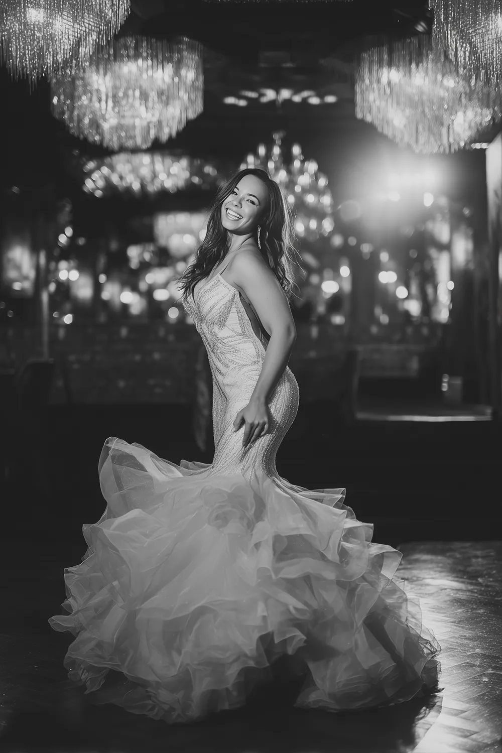 Smiling curvy teen girl in glamorous mermaid prom dress posing on prom dance floor with chandeliers