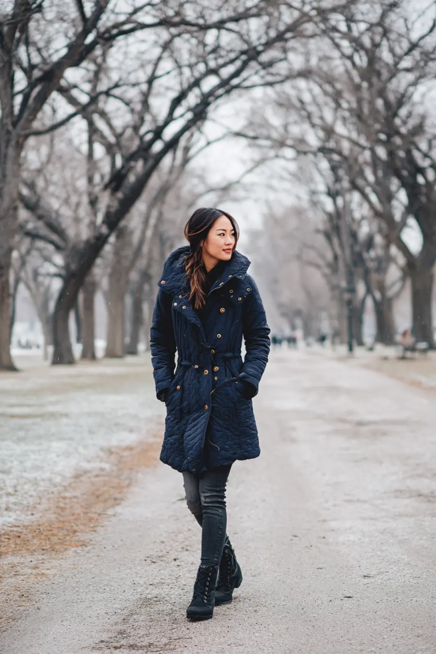 woman in long navy quilted jacket ankle boots frosty park pathway winter look