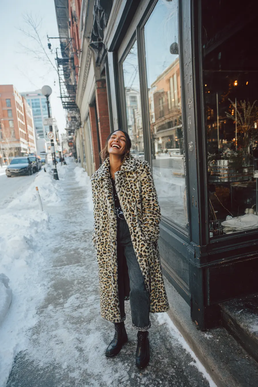 woman laughing in animal print coat and dark jeans winter city street editorial style